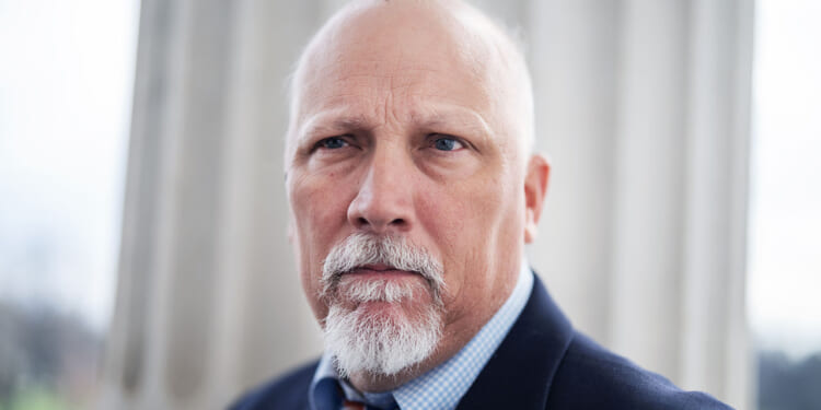 Rep. Chip Roy, sponsor of the SAVE America Act. Pictured: A serious-looking older man with a bald head, white beard, and mustache, wearing a suit and tie, stands in front of a large white column.