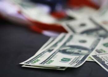 Money is scattered on a table on top of an American flag.