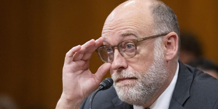 Groups that received federal grants oppose OMB's new grantmaking rules. Pictured: OMB Director Russell Vought, a man with glasses, a bald head, and a white beard sits at a microphone, holding his glasses and looking attentive in a formal setting.