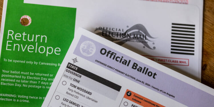 Close-up of a green return envelope, an official election mail envelope, and a partially visible official ballot for a primary election.