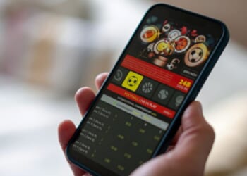 A phone screen is displayed with a gambling app on the interface.