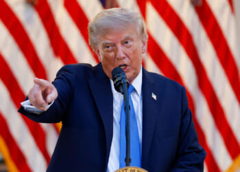 The Supreme Court rules on Trump's mail-in ballot regulations. Pictured: President Donald Trump, a man in a navy suit speaks into a microphone and points forward, with a backdrop of several American flags displayed in rows behind him.