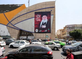 Motorists drive vehicles past a billboard depicting Iran's late supreme leader Ali Khamenei along a street in central Tehran on Aug. 8, 2026.