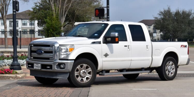 A white 2013 Ford F-250 Super Duty truck sits in the road in Houston, Texas.