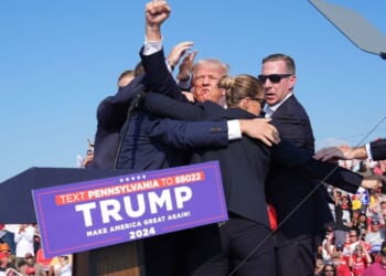 Former president Donald Trump, surrounded by Secret Service officers, raises his arm with blood on his face after an assassination attempt during a campaign rally July 13, 2024, in Butler, Pennsylvania.