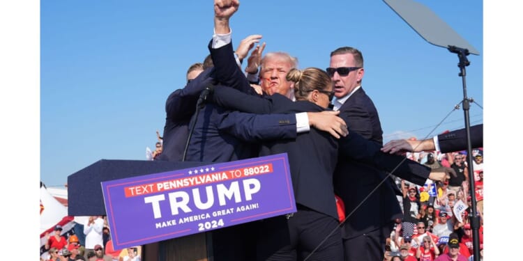 Former president Donald Trump, surrounded by Secret Service officers, raises his arm with blood on his face after an assassination attempt during a campaign rally July 13, 2024, in Butler, Pennsylvania.
