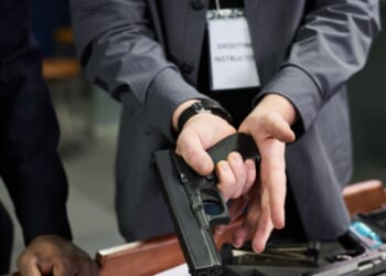 A close-up shot of an instructor demonstrating proper firearm safety.