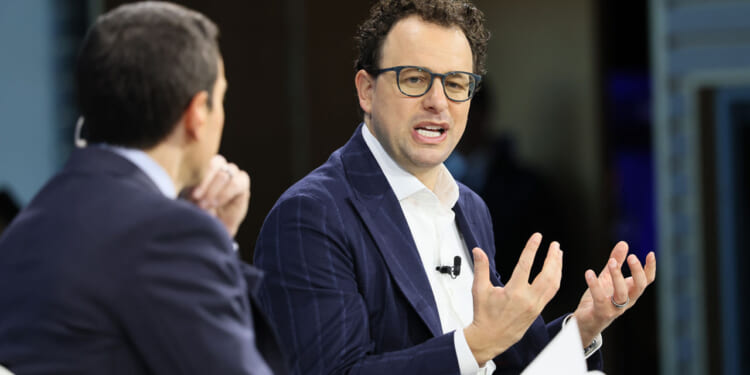 Dario Amodei and another man sit and talk during an interview or panel discussion.